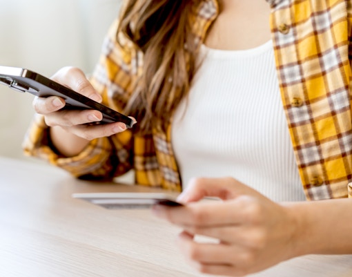 Person using a smartphone and credit card for online booking.