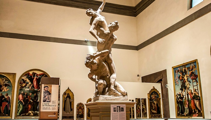 Visitors exploring art at Uffizi & Accademia Galleries, Florence, with audio guide.