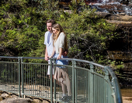 Couple walking on a trail near a waterfall in Blue Mountains during sunset, Sydney day trip.