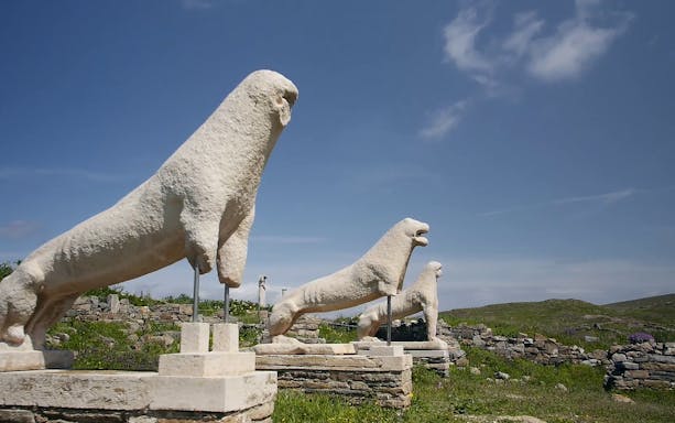Stone lion statues at Delos Archaeological Site under a clear sky.