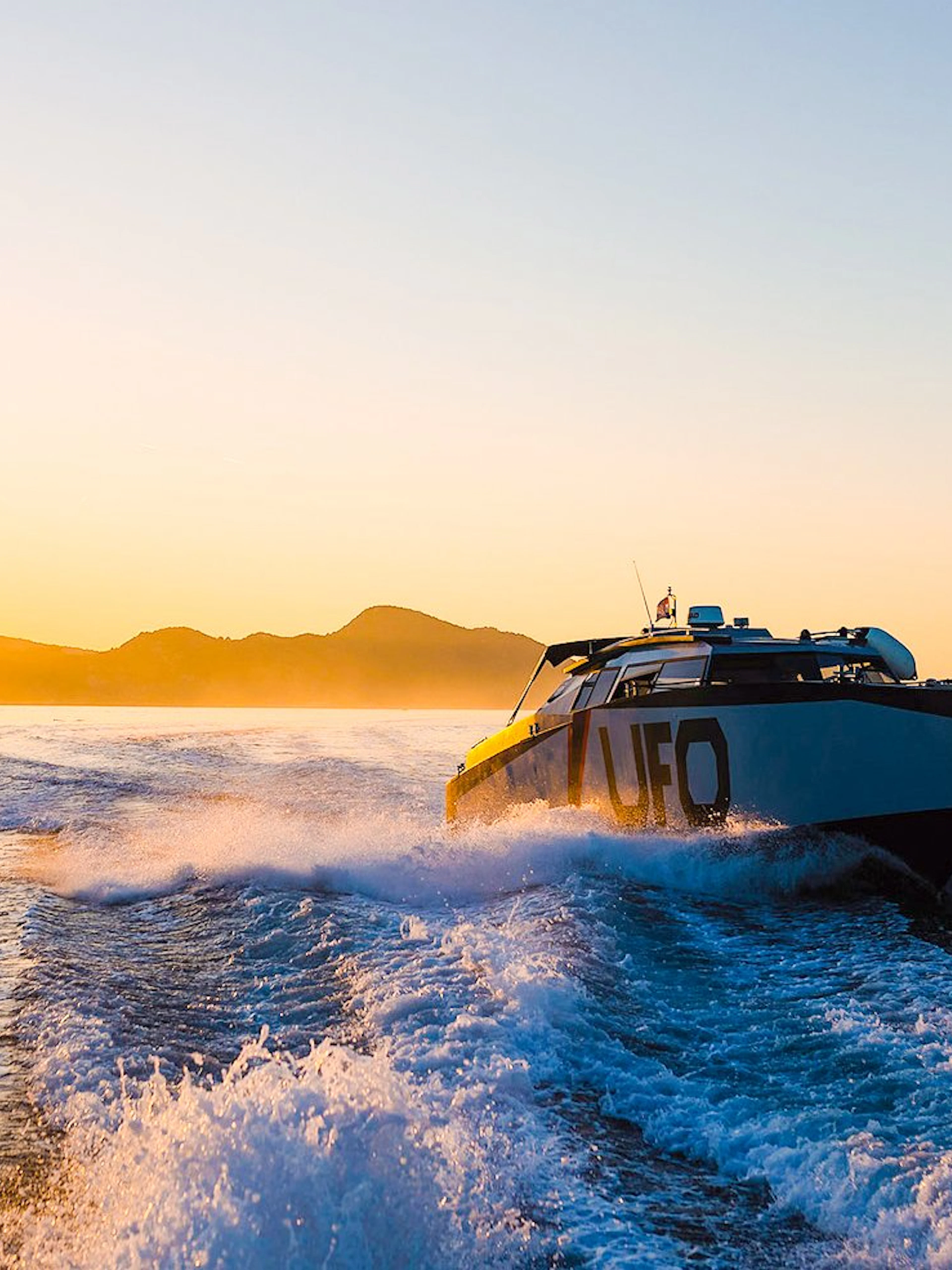 Boat cruising at sunset near Dubrovnik with distant mountains.