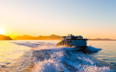 Boat cruising at sunset near Dubrovnik with distant mountains.
