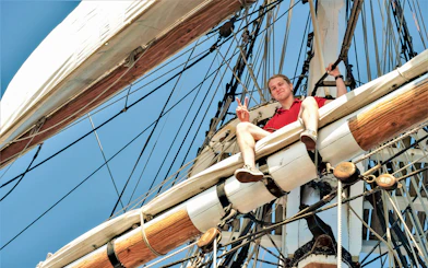 Man sitting on the mast of a tall ship during a Sydney Harbour cruise.