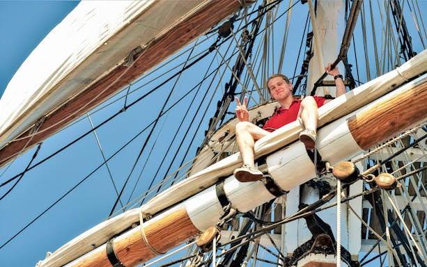 Man sitting on the mast of a tall ship during a Sydney Harbour cruise.