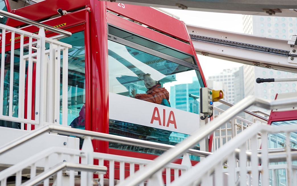 Hong Kong Observation Wheel cabin with passenger and cityscape background.