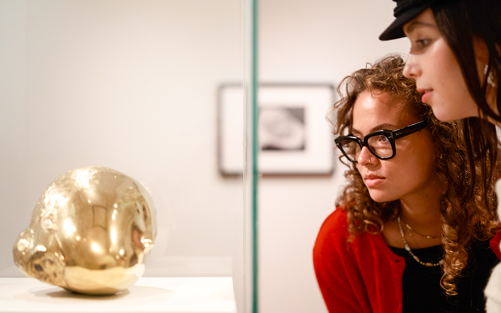 Visitors observing a golden sculpture at the H’ART Museum exhibit.