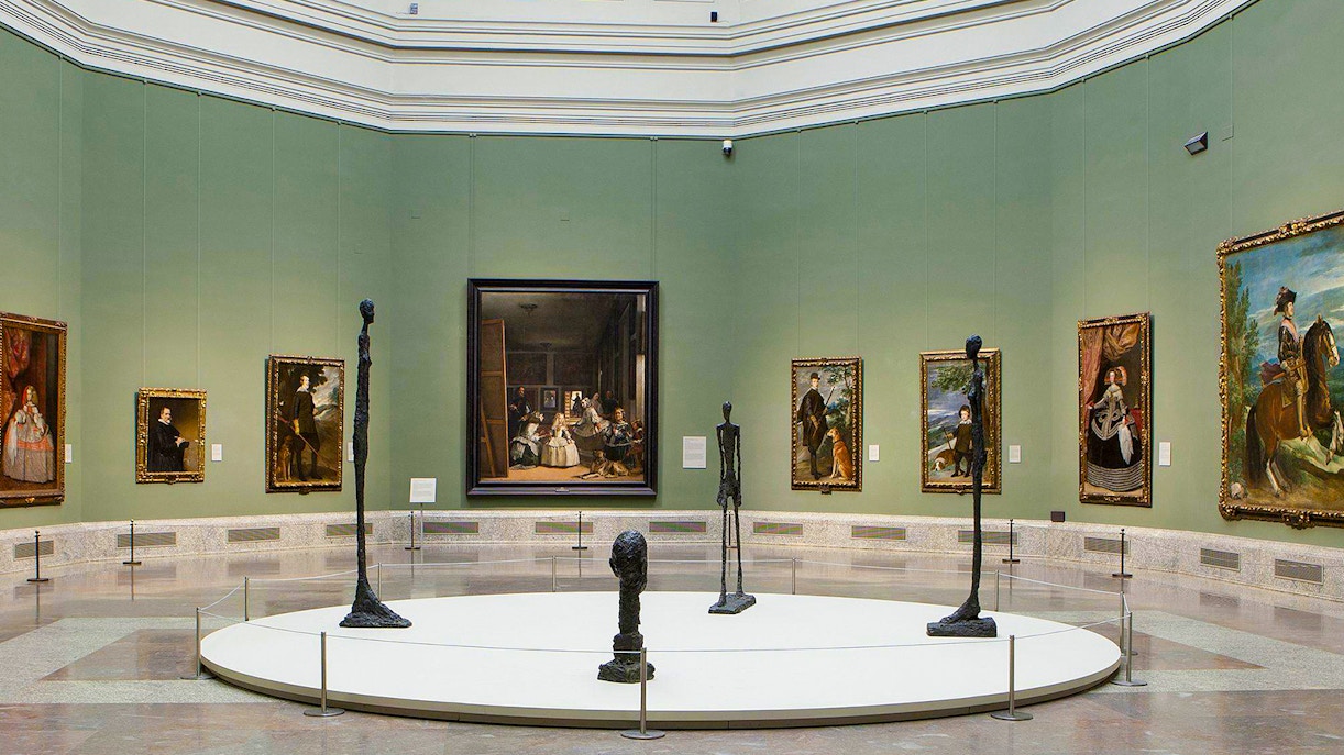Visitors exploring art exhibits inside the Prado Museum, Madrid, during a guided tour.