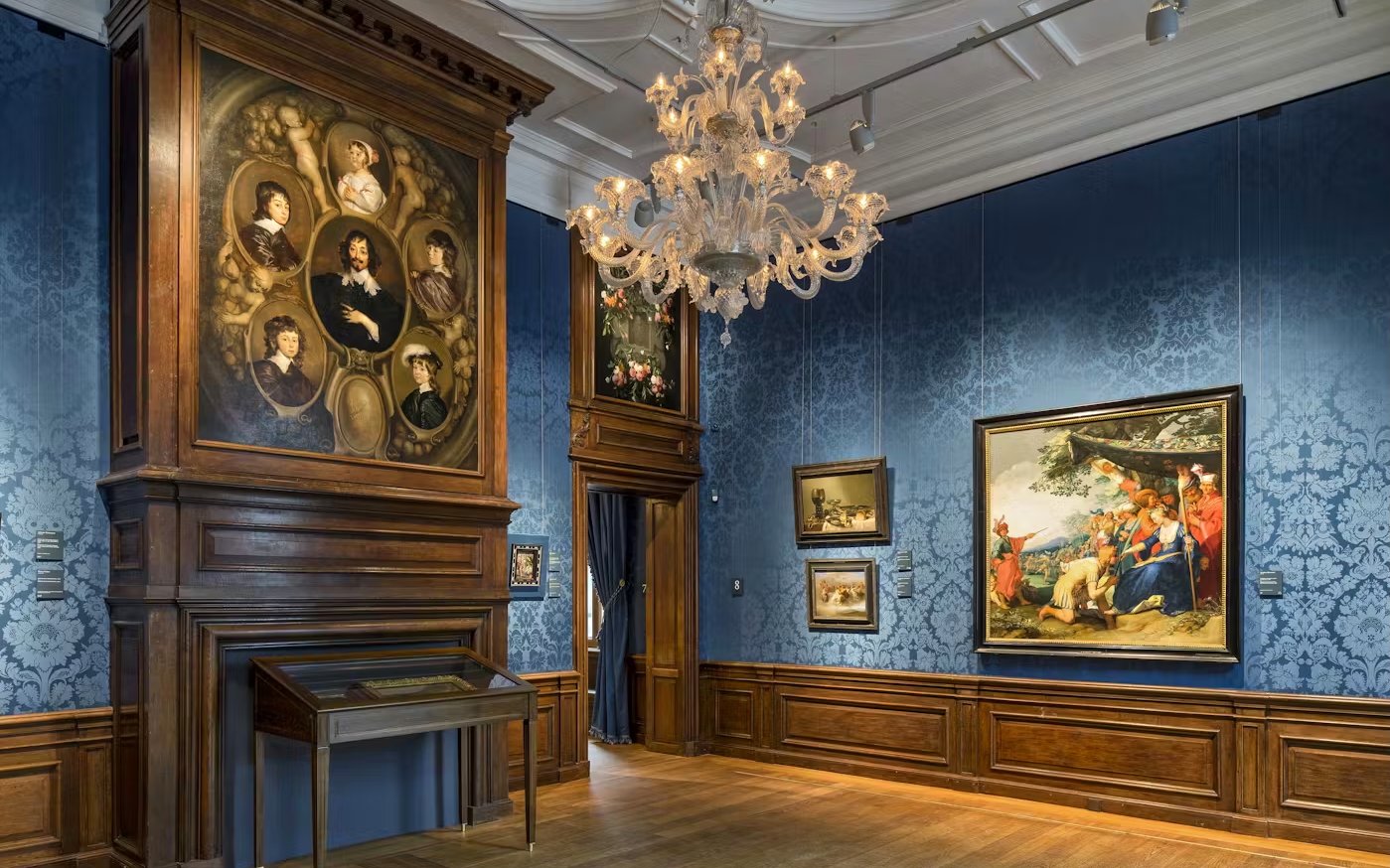 Mauritshuis museum gallery with classic paintings and ornate chandelier.