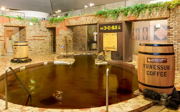 Hakone Kowakien Yunessun coffee-themed hot spring with wooden barrels and brick decor.