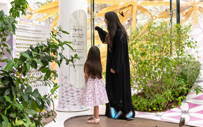Visitors exploring the Butterfly House at Al Noor Island, surrounded by plants and butterflies.