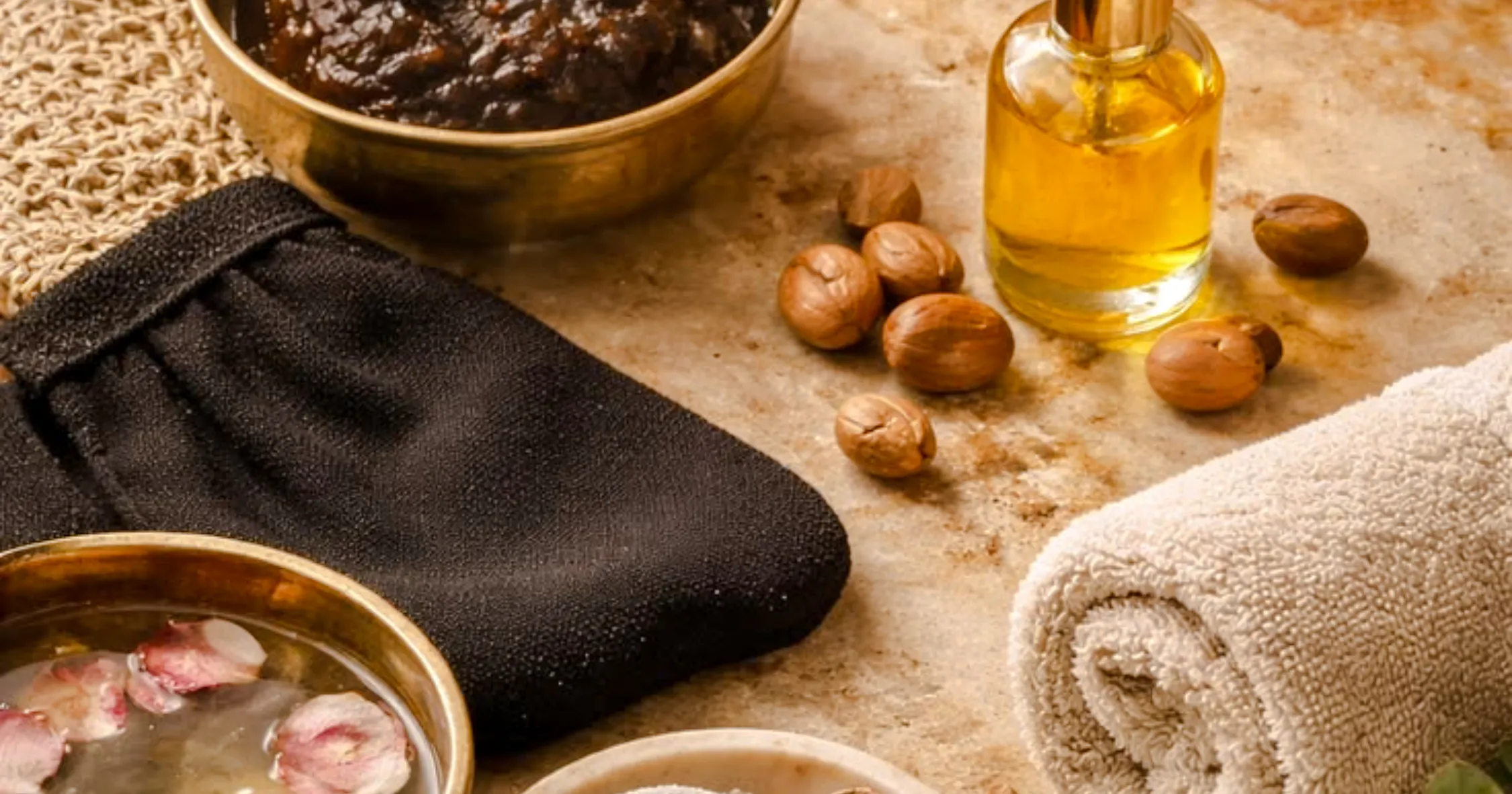 Traditional Marrakchi hammam items with black glove, oil, and nuts in Marrakesh spa setting.