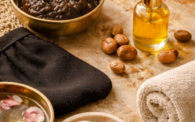 Traditional Marrakchi hammam items with black glove, oil, and nuts in Marrakesh spa setting.