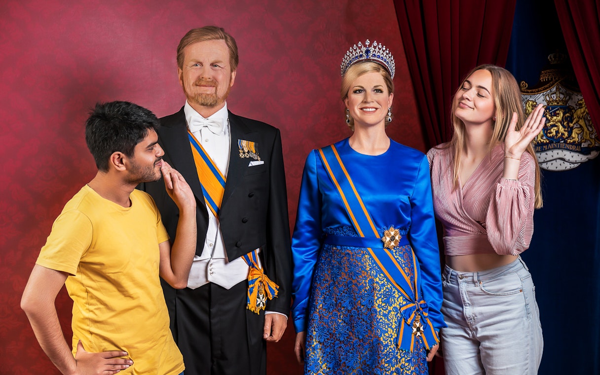 Visitors posing with wax figures at Madame Tussauds Amsterdam.