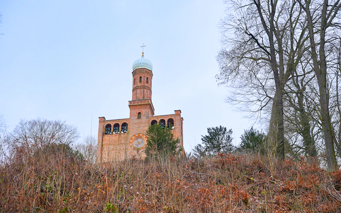 St. Peter und Paul Church tower in Nikolskoe, Berlin, surrounded by trees.