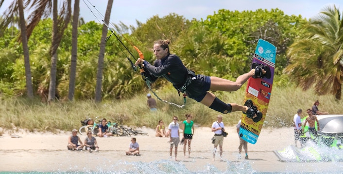 Kite surfer catching air over waves near Miami beach.