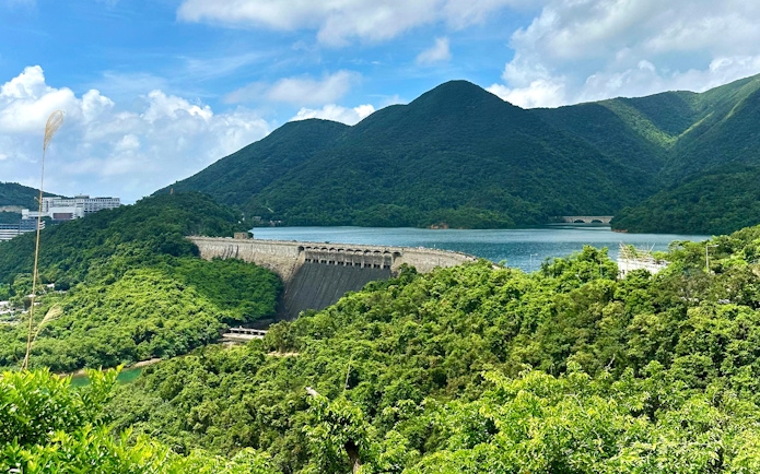 Scenic view of lush green hills and a dam near a lake on the Big Bus Hop-On Hop-Off Tour.