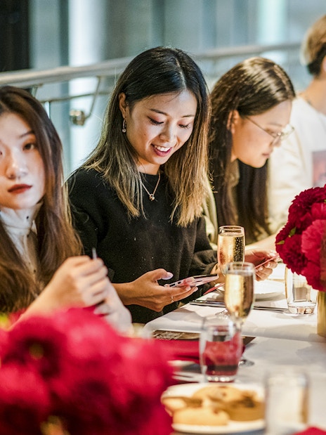 Guests enjoying high tea at National Gallery of Victoria with red floral arrangements.