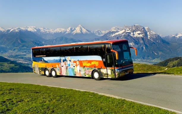 Original Sound of Music tour bus with Alps in the background.