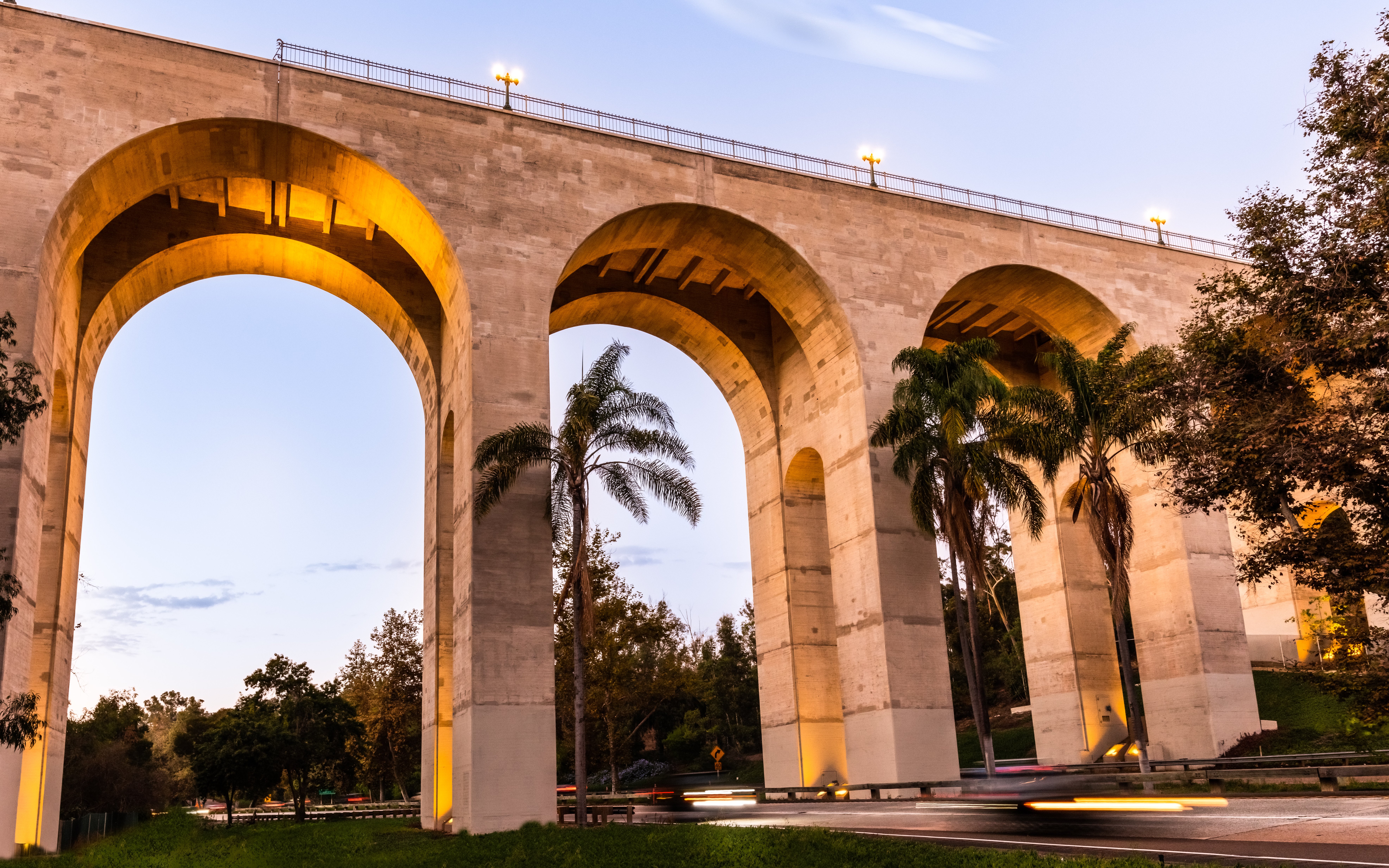 Cabrillo Bridge arches with palm trees in San Diego at dusk.