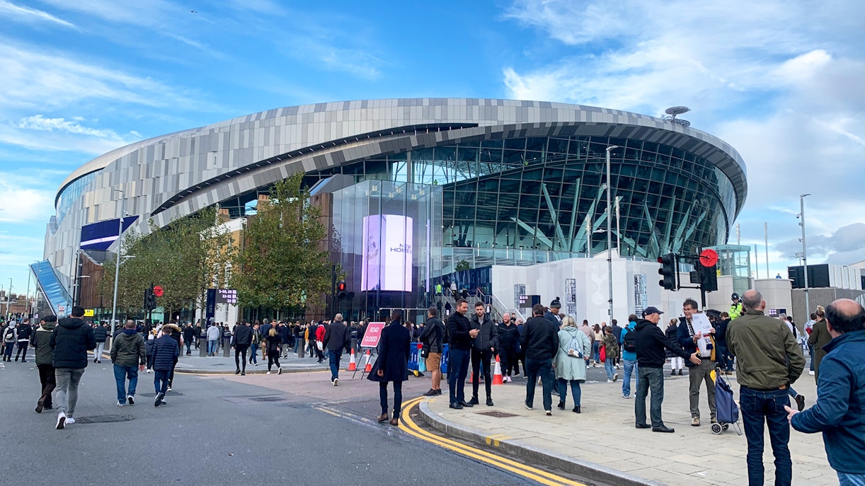 Crowd outside Tottenham Hotspur Stadium in London on a clear day.