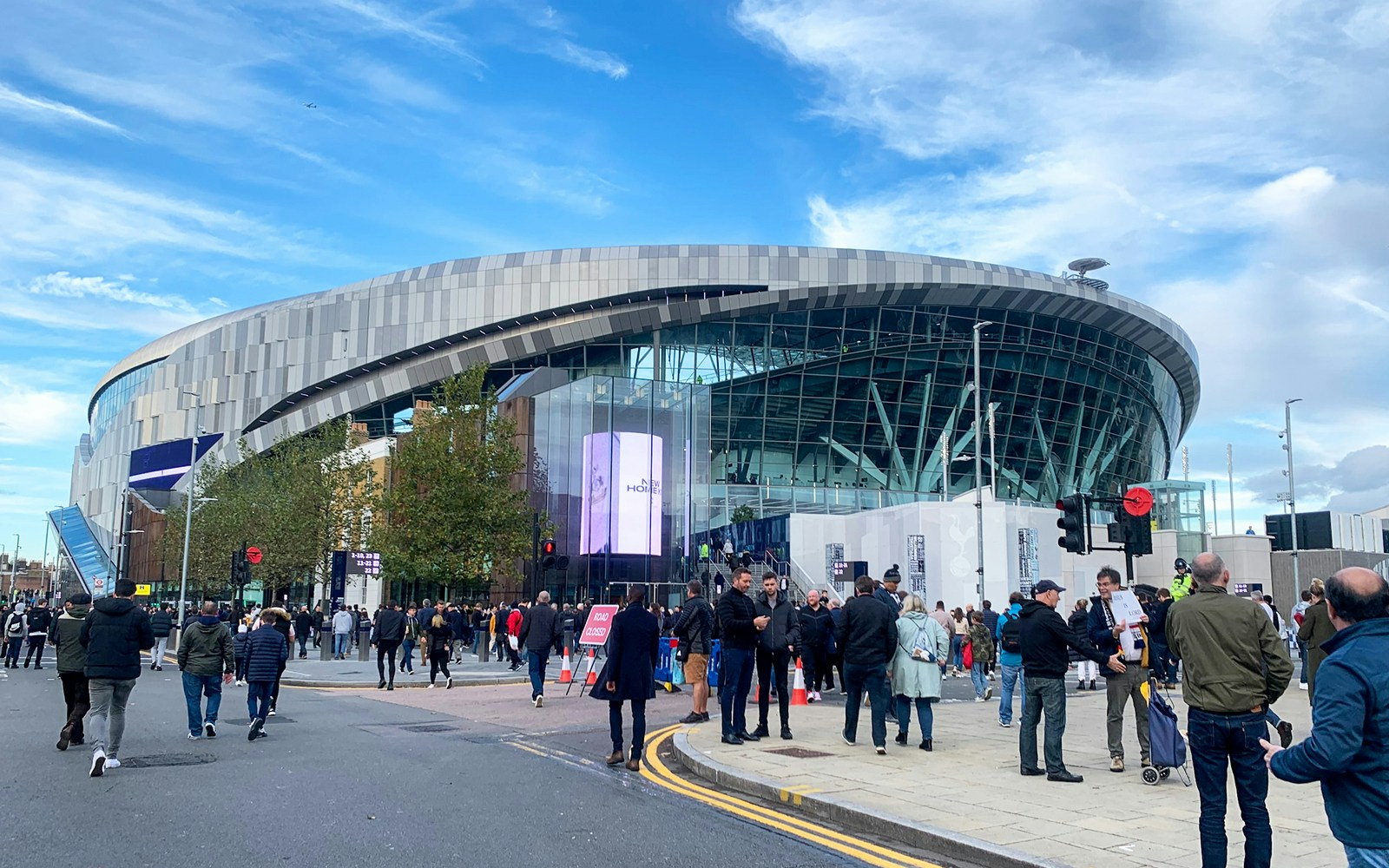 Crowd outside Tottenham Hotspur Stadium in London on a clear day.