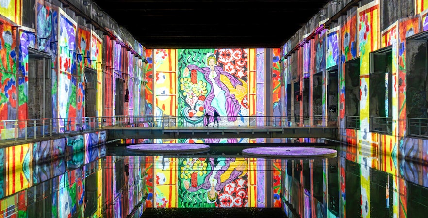 Matisse artwork projections at Bassins des Lumières exhibition, vibrant colors reflecting on water.