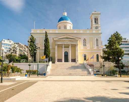 Agios Nikolaos Church in Athens with blue dome and surrounding trees.