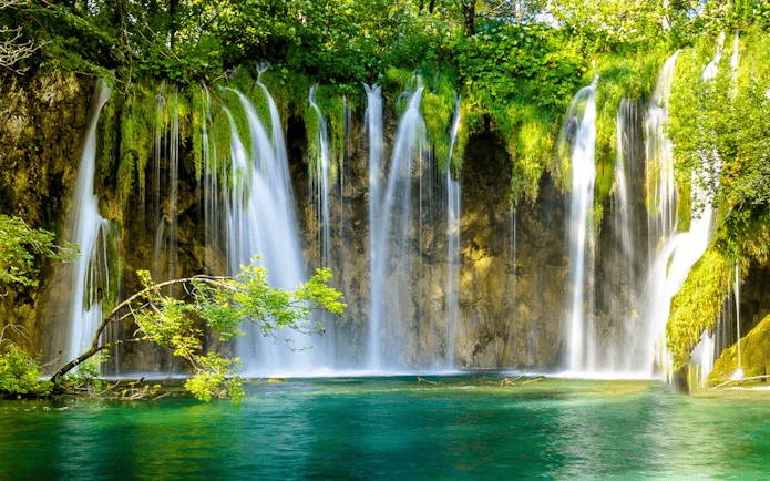 Waterfalls cascading into turquoise water at Plitvice Lakes, Croatia.