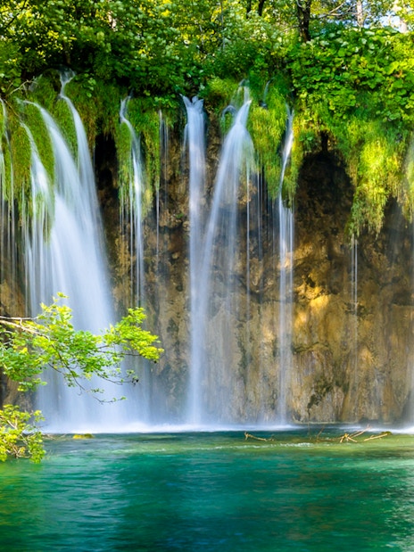 Waterfalls cascading into turquoise water at Plitvice Lakes, Croatia.