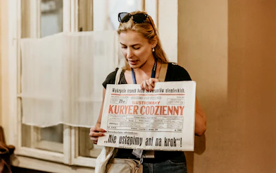 Guide holding a historical newspaper during a tour at Oskar Schindler's Factory in Krakow.
