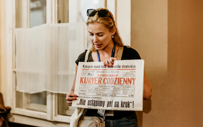 Guide holding a historical newspaper during a tour at Oskar Schindler's Factory in Krakow.
