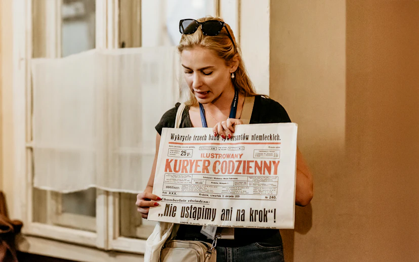Guide holding a historical newspaper during a tour at Oskar Schindler's Factory in Krakow.
