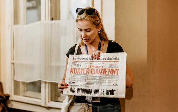 Guide holding a historical newspaper during a tour at Oskar Schindler's Factory in Krakow.