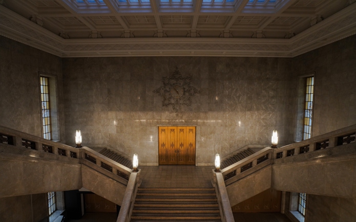 Grand staircase inside the Honkan of the Tokyo National Museum with ornate lighting.