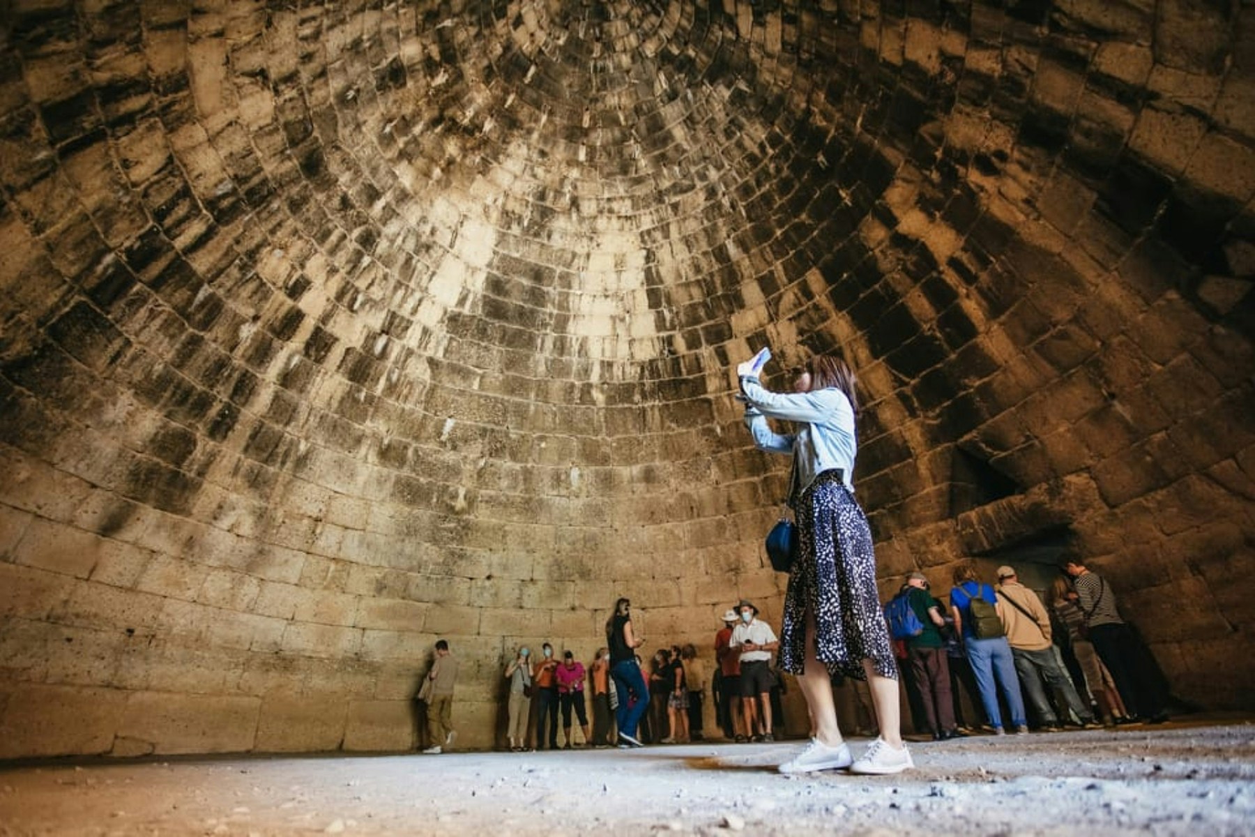 Tourists exploring the interior of the round tomb of Agamemnon in Mycenae.