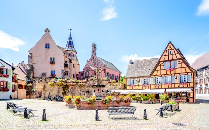 Colorful half-timbered houses and a fountain in Eguisheim, France.