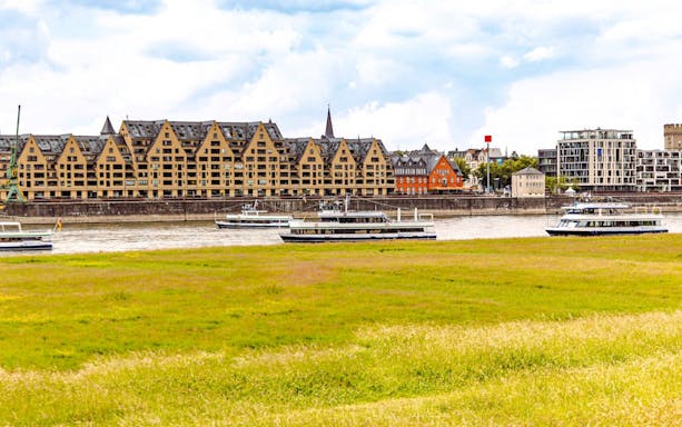 Cologne Rhine River cruise boats with city skyline and historic buildings in view.