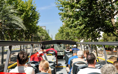 Open-top bus tour in Barcelona with passengers viewing city landmarks.