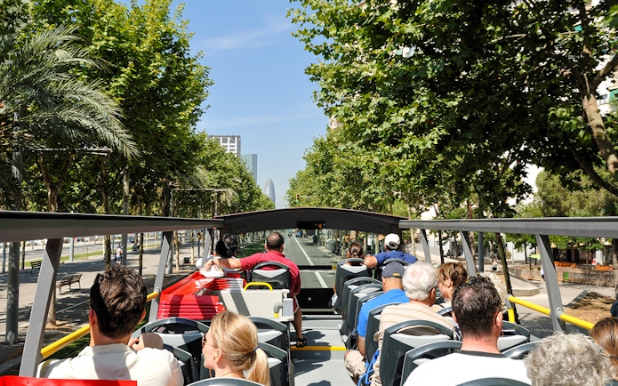 Open-top bus tour in Barcelona with passengers viewing city landmarks.