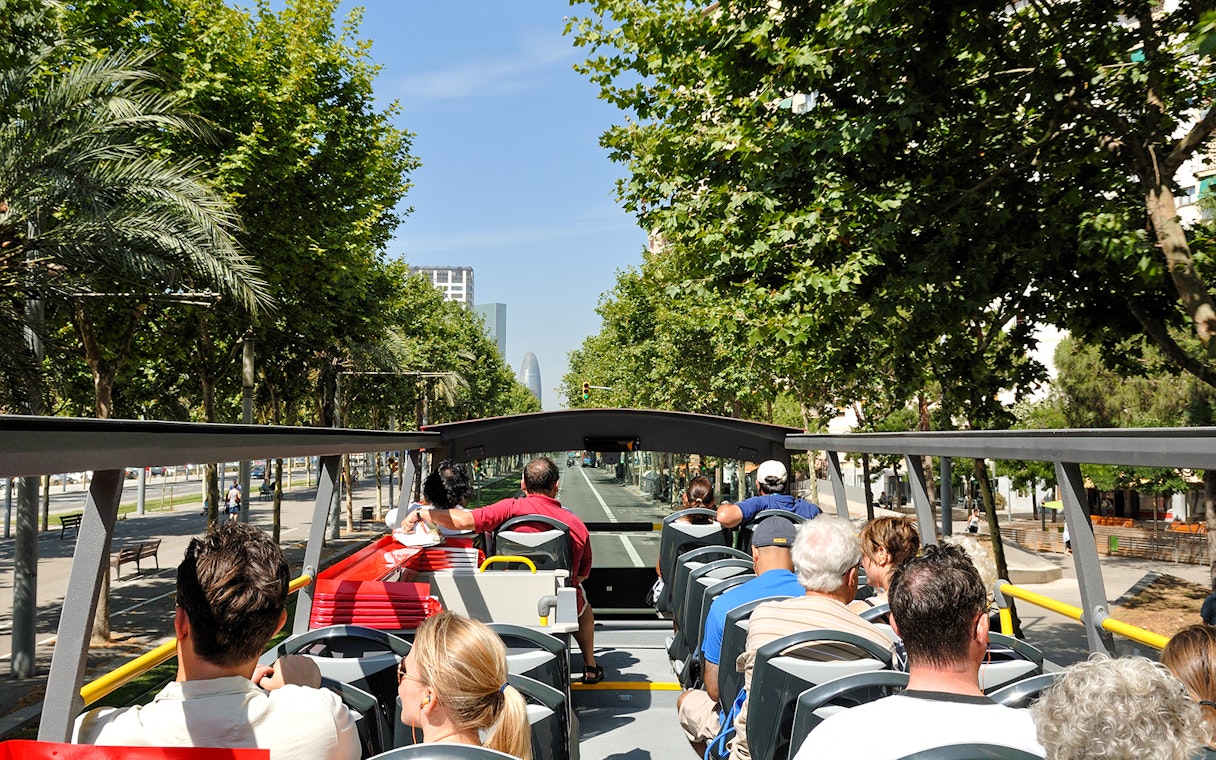 Open-top bus tour in Barcelona with passengers viewing city landmarks.