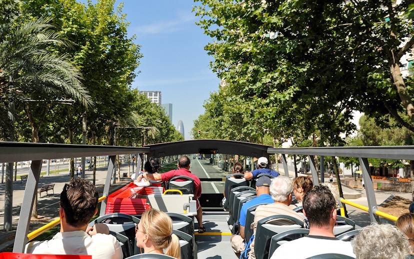 Open-top bus tour in Barcelona with passengers viewing city landmarks.