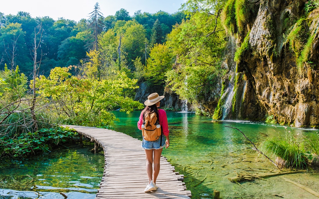 Guest walking on wooden path by waterfalls at Plitvice Lakes, Croatia.