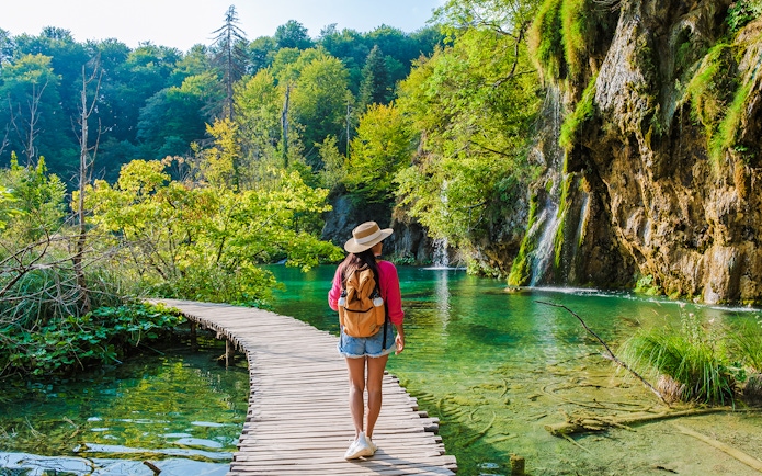 Guest walking on wooden path by waterfalls at Plitvice Lakes, Croatia.