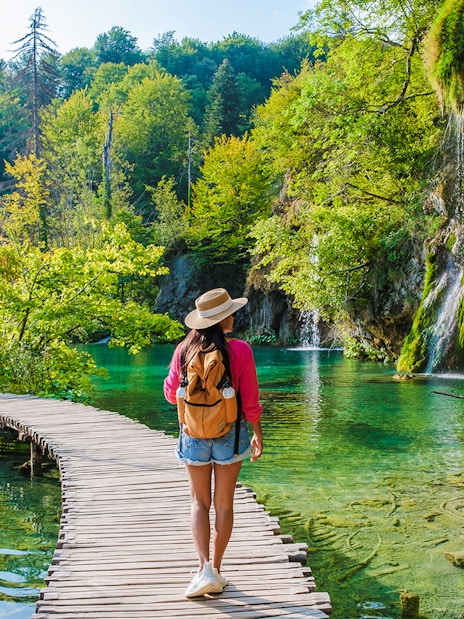 Guest walking on wooden path by waterfalls at Plitvice Lakes, Croatia.