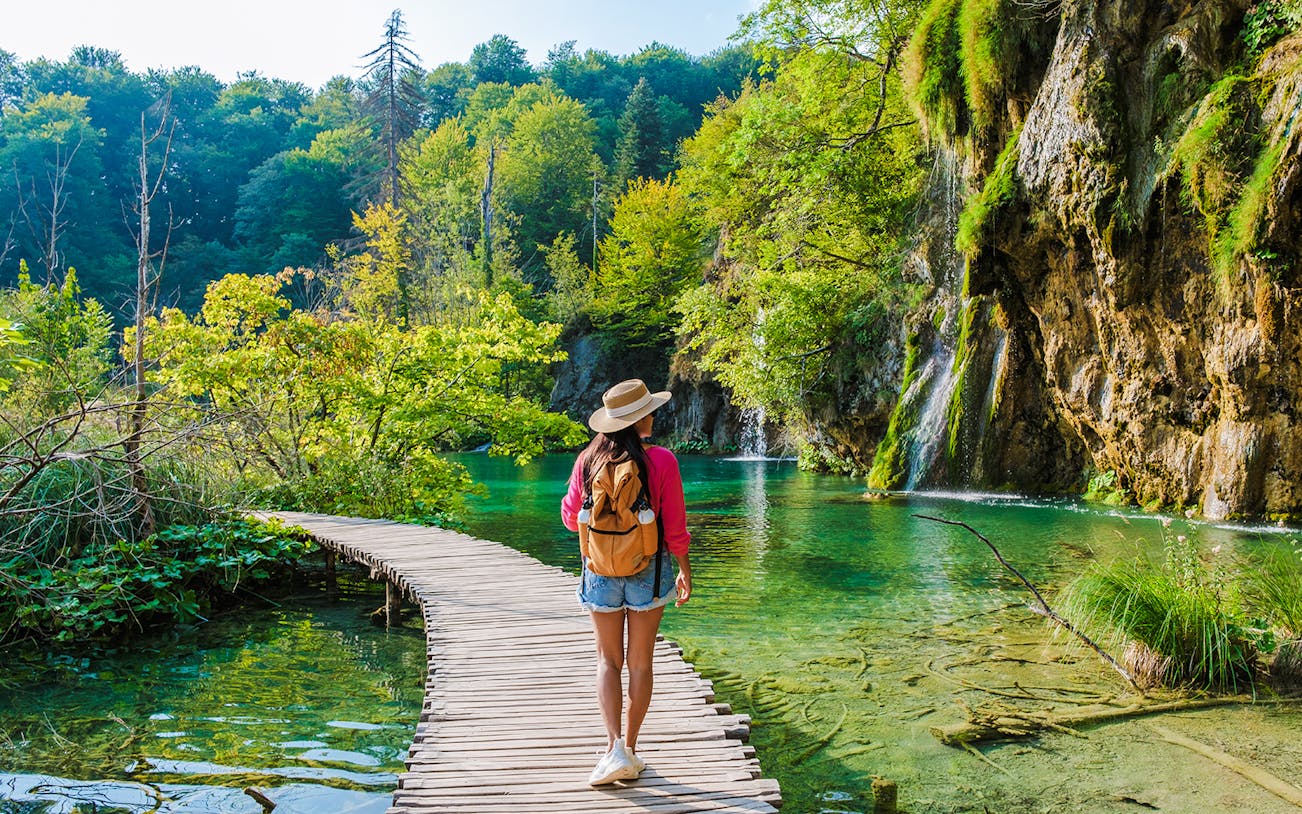 Guest walking on wooden path by waterfalls at Plitvice Lakes, Croatia.