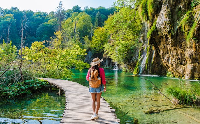 Guest walking on wooden path by waterfalls at Plitvice Lakes, Croatia.