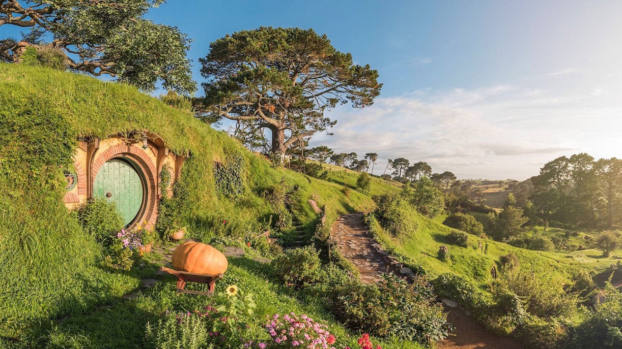 Hobbiton Movie Set with round door and lush greenery, part of Auckland tour.