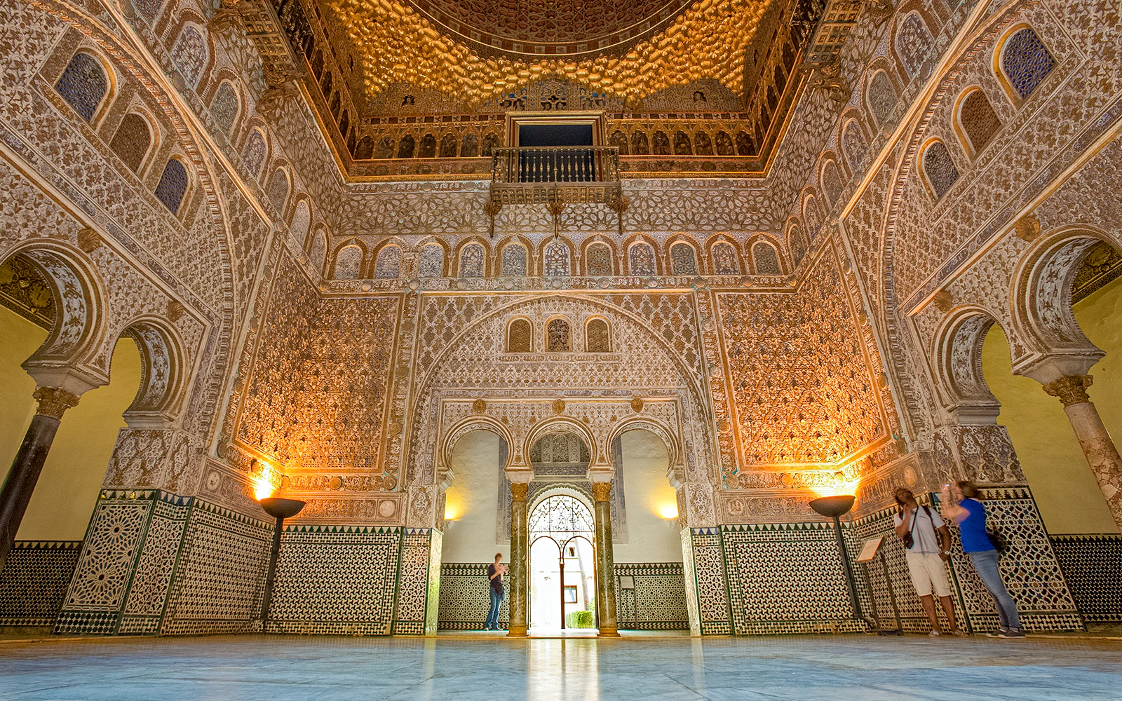 Ornate interior of the Alcazar of Seville with intricate tilework and arches.
