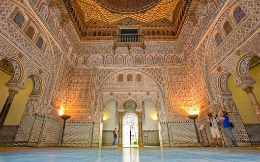 Ornate interior of the Alcazar of Seville with intricate tilework and arches.