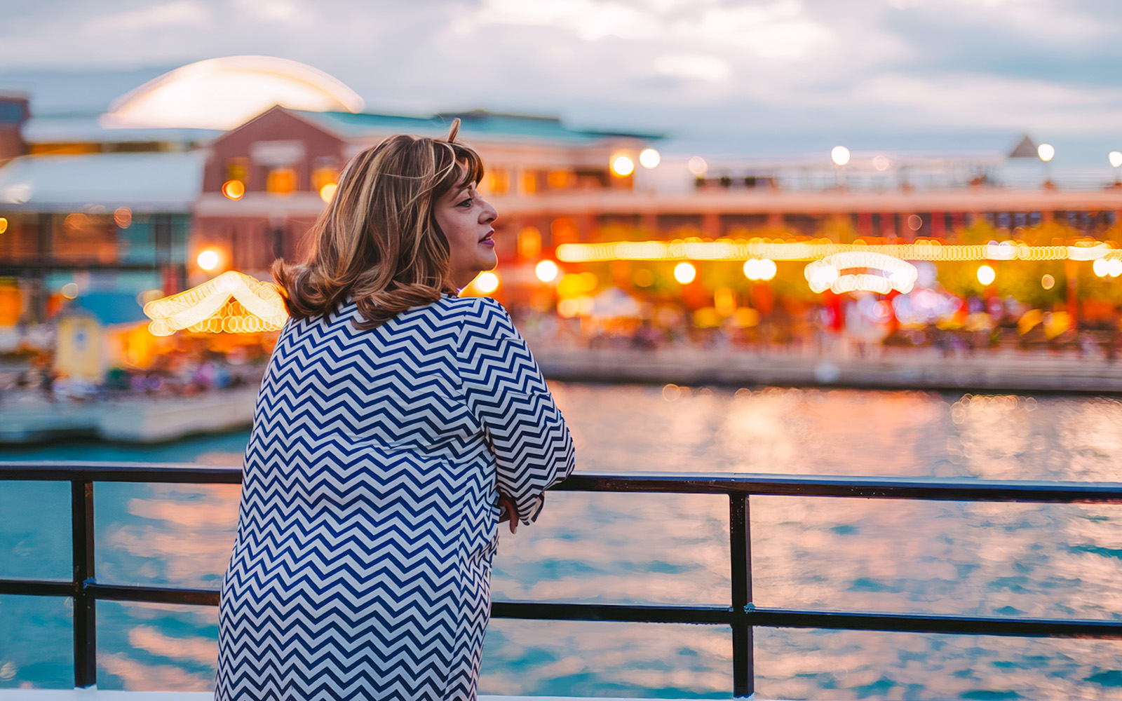 Woman enjoying Chicago skyline from a dinner cruise at sunset.